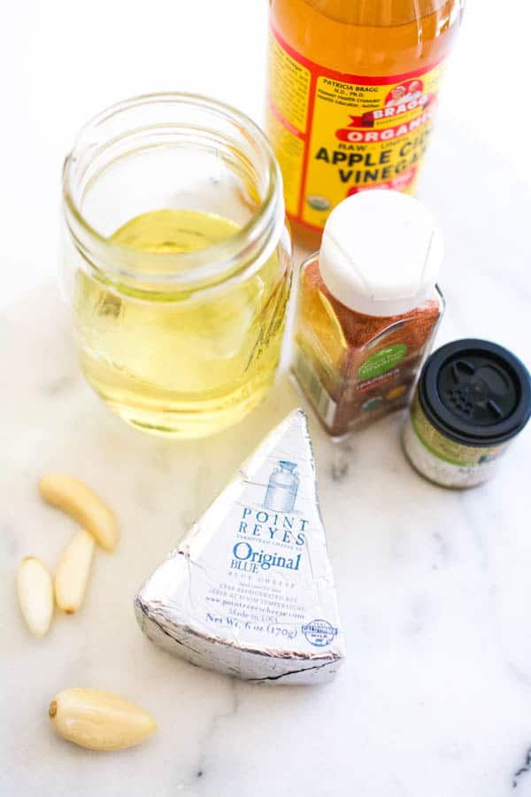 Blue cheese wedge next to garlic and other dressing ingredients.