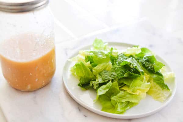 Romaine salad on a plate next to a jar of blue cheese vinaigrette dressing.