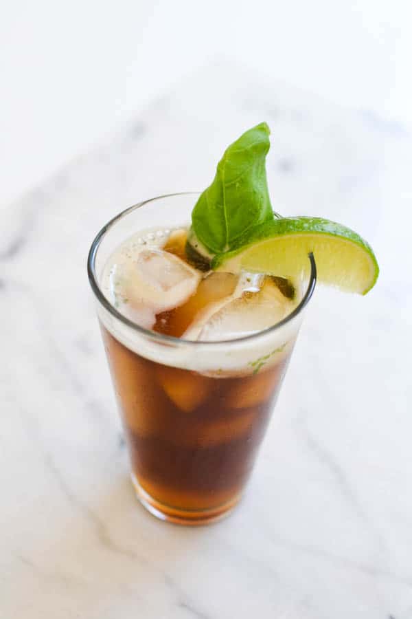 My favorite iced tea with fresh basil in a glass on a table with a lime wedge.