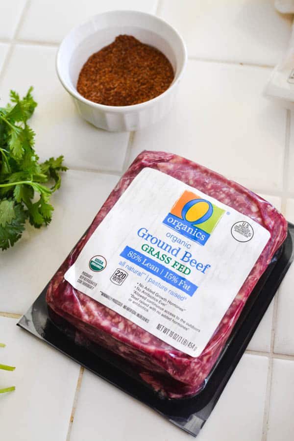 ground beef next to taco seasoning and cilantro on a counter