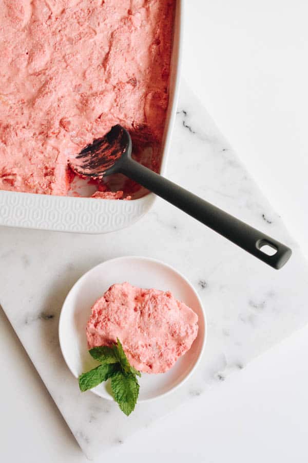 Strawberry Jello angel food cake dessert in a baking dish next to a plate with a serving of the easy dessert