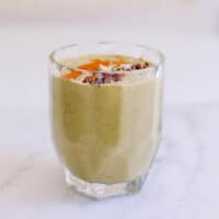 Avocado Banana Smoothie in a glass topped with chia seeds, cinnamon and cocoa nibs.