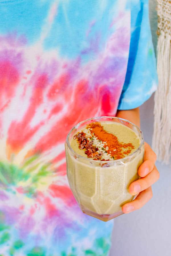 Kid's hand holding a glass with Banana Avocado Smoothie.