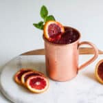 Close up of a Blood Orange Mule topped with a blood orange slice and fresh mint.