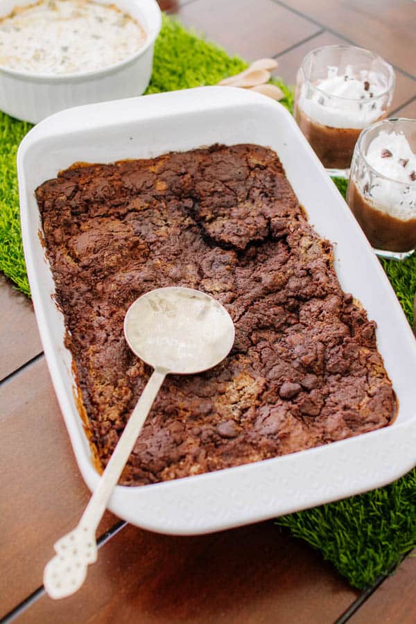 Chocolate dump cake in a baking dish with a serving spoon.