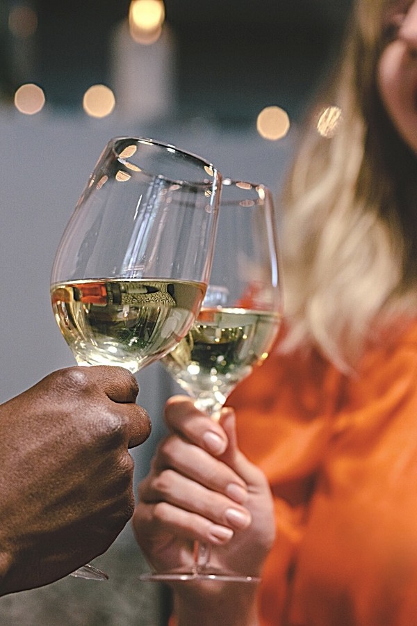 Man and women clinking wine glasses in a cheers.
