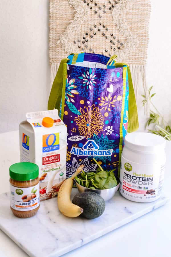 Ingredients to make a green smoothie next to an Albertsons grocery bag.