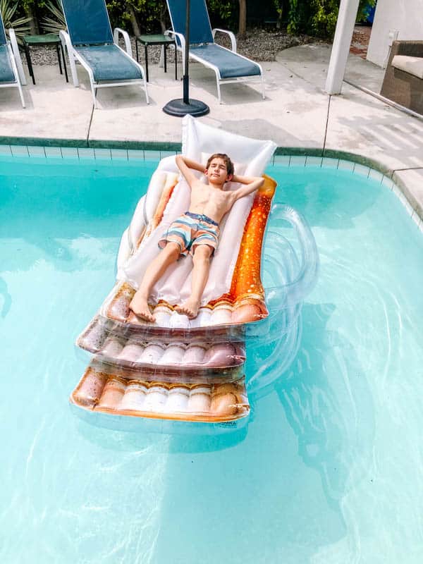Kid laying on 4 stacked pool rafts on top of each other.