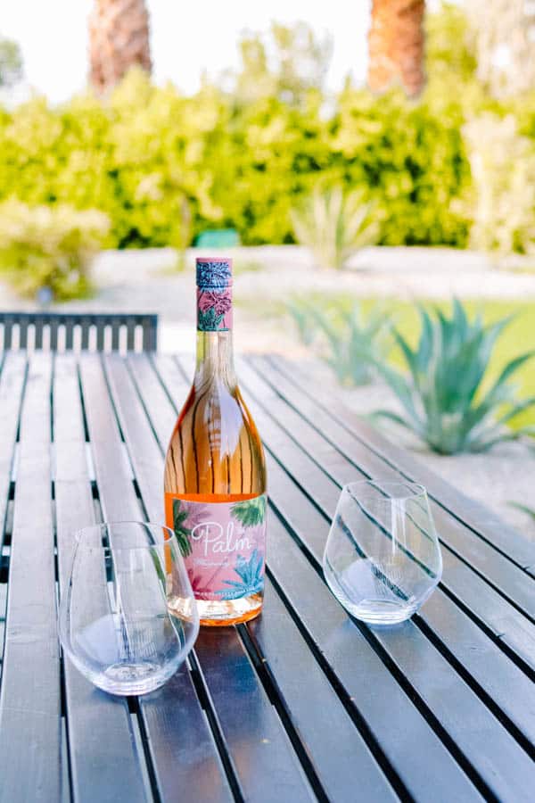 Bottle of rose and glasses on an outdoor dining table.