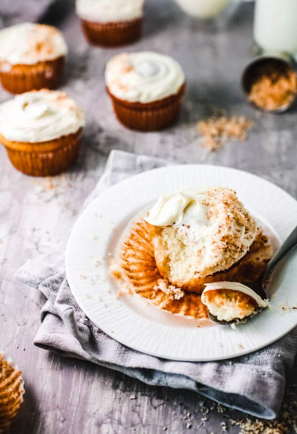 Coconut rum cupcake on a plate with a piece cut out with a fork on a dessert plate.