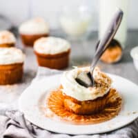 Square cropped image of a frosted coconut cupcake with a fork sticking out.