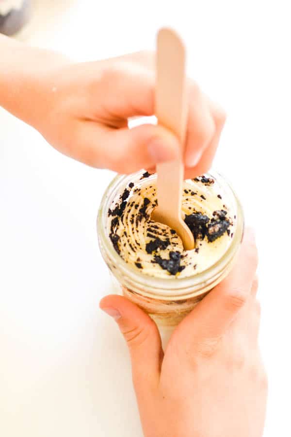 Top view of a kid eating a cookies and cream cupcake in a jar.