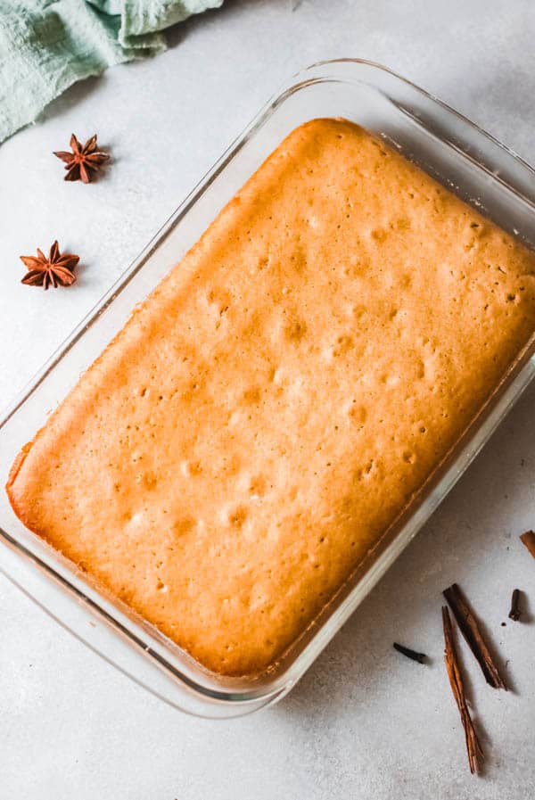 Baked Pumpkin Cake in a glass baking dish on a table with spices laying around it.