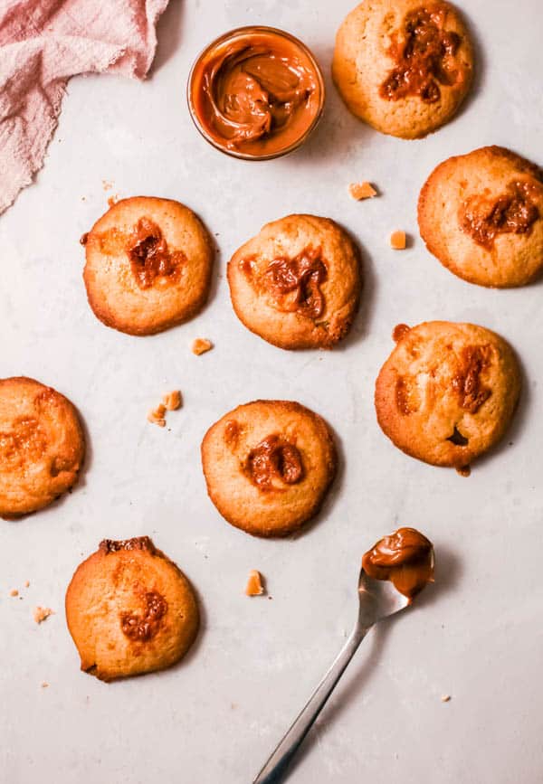 Baked cookies with butterscotch scattered on a table with a spoon holding a dallop of butterscotch.