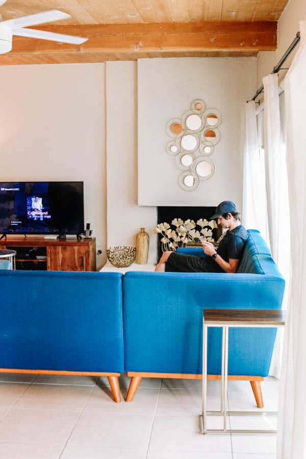 Mid century modern living room with man sitting on the couch and looking at his phone.