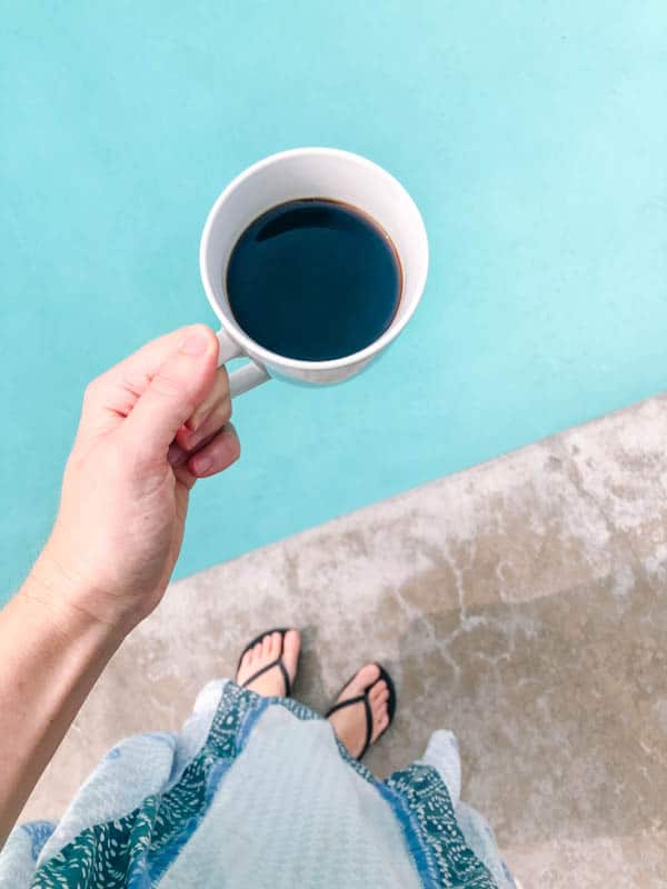 Woman holding coffee next to a pool.