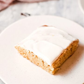 Easy pumpkin cake topped with cream cheese frosting on a white plate.