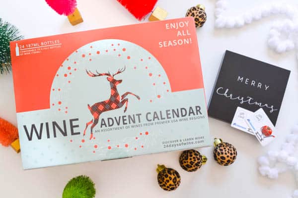 Wine advent calendar box on a table with some holiday decor around it and 2 gift cards to Albertsons.
