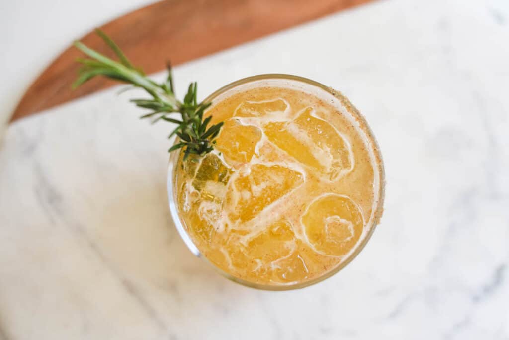 View of a cocktail with ice from above with a rosemary sprig.