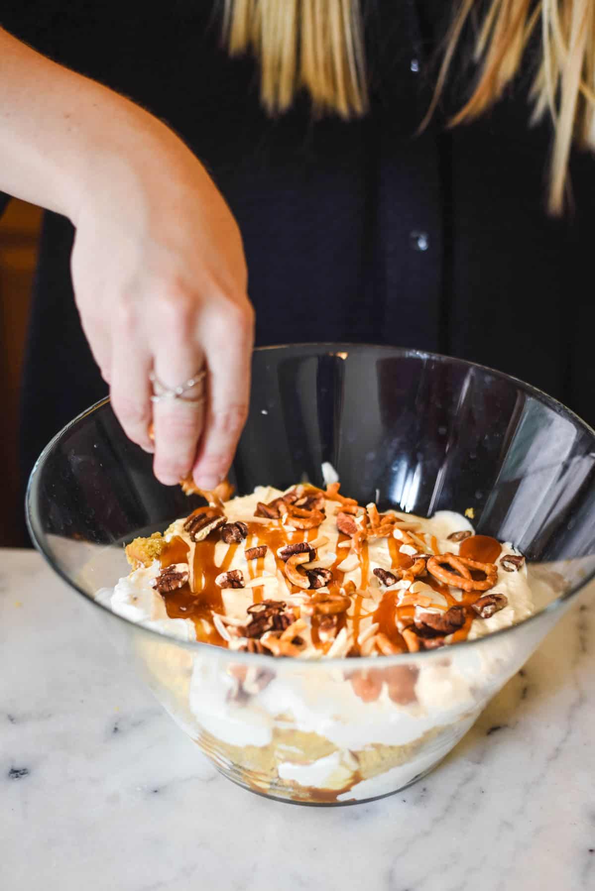 Add nuts to the top of a Pumpkin Trifle dessert on a cutting board.