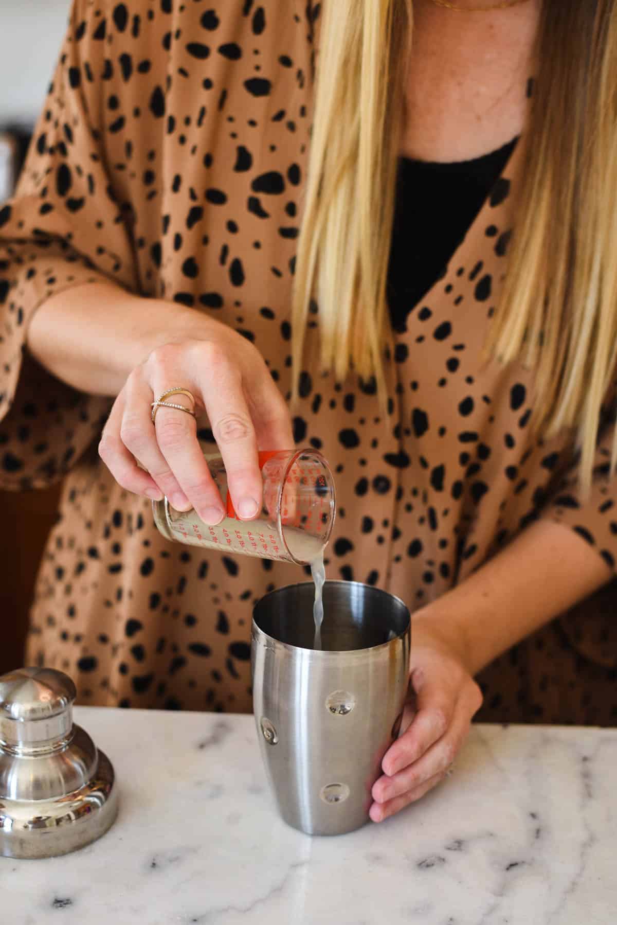 Woman pouring lime juice into a cocktail shaker.
