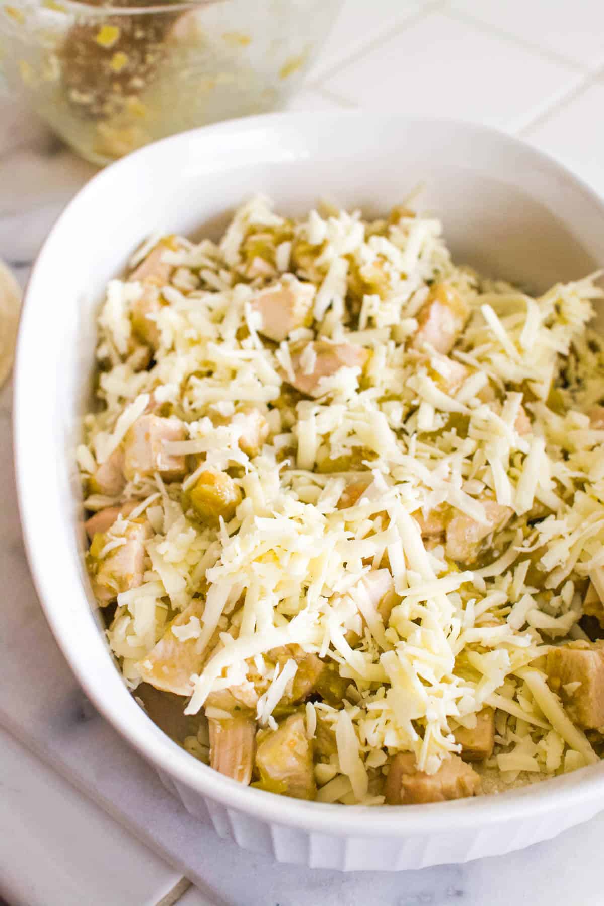 Layered Swiss enchilada casserole with chopped chicken in a baking dish.