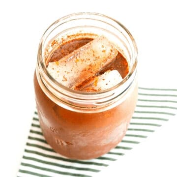 Close up of a jar holding iced coffee topped with fresh grated nutmeg.