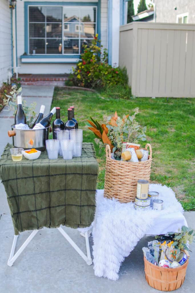 Small tables with wine and canned foods to donate for a fun holiday open house idea.