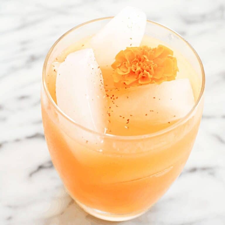 Spiced Pear Cocktail on a counter with an edible flower garnish.