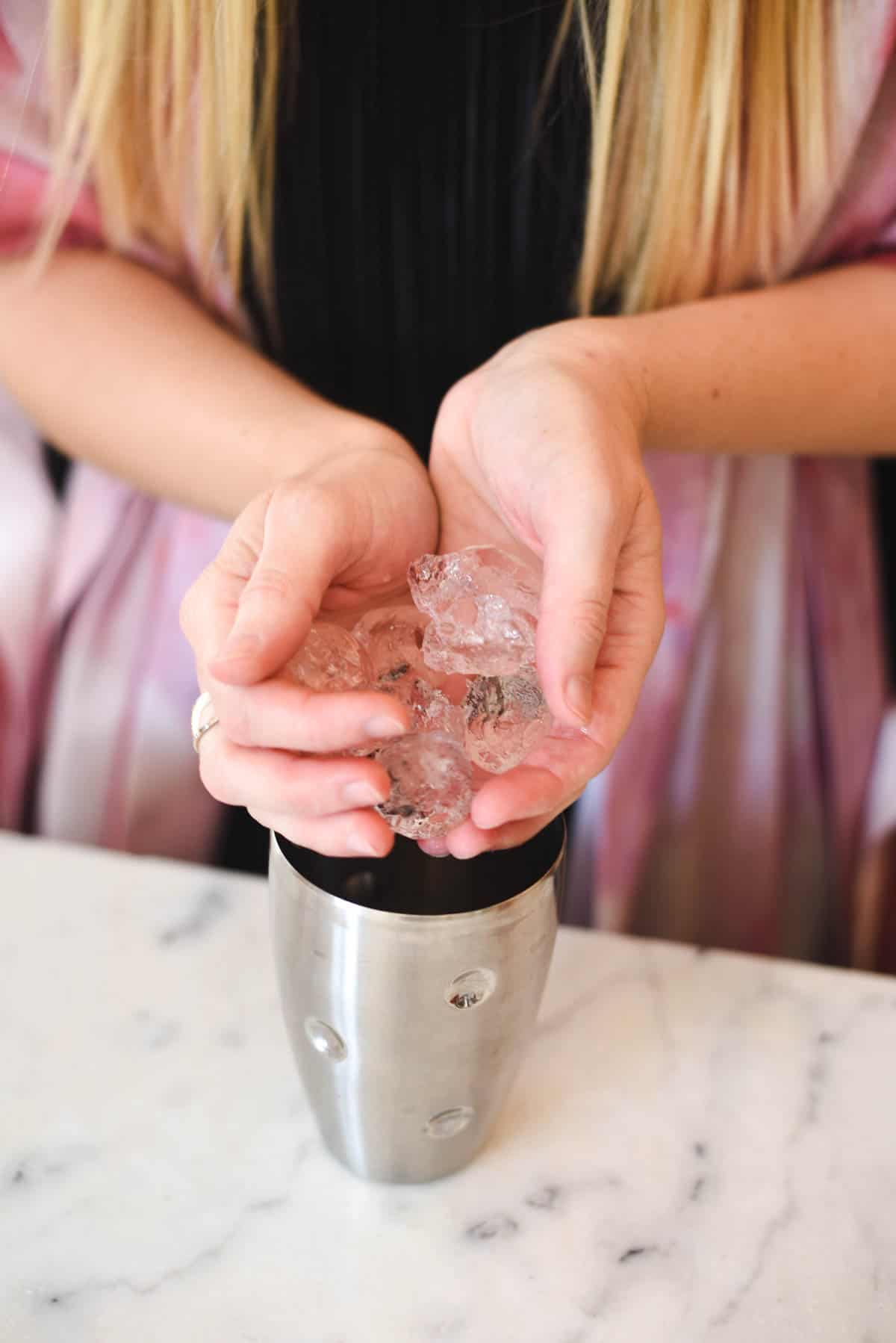 Woman adding ice to a cocktail shaker.