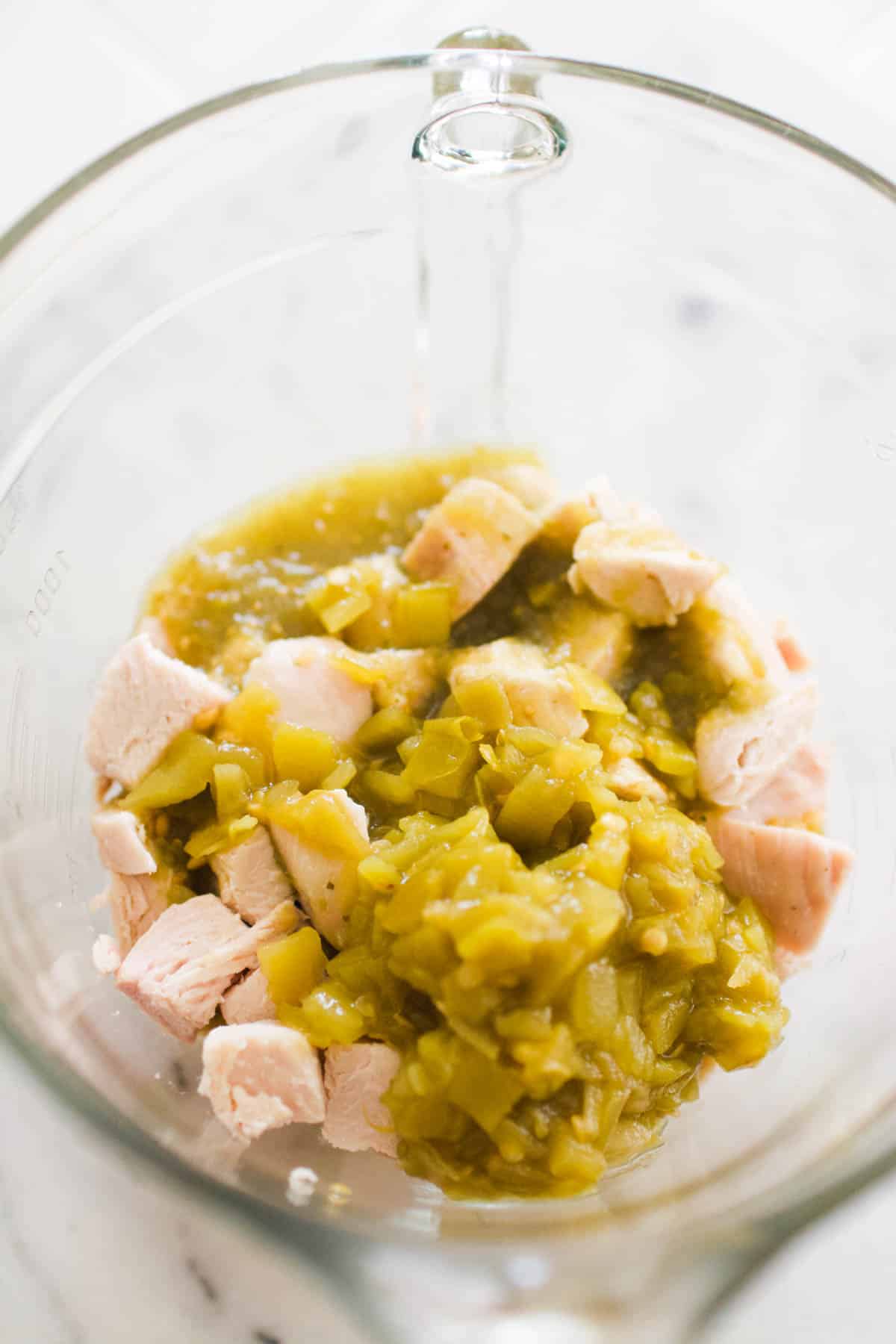 Glass bowl with diced green chiles and chopped chicken