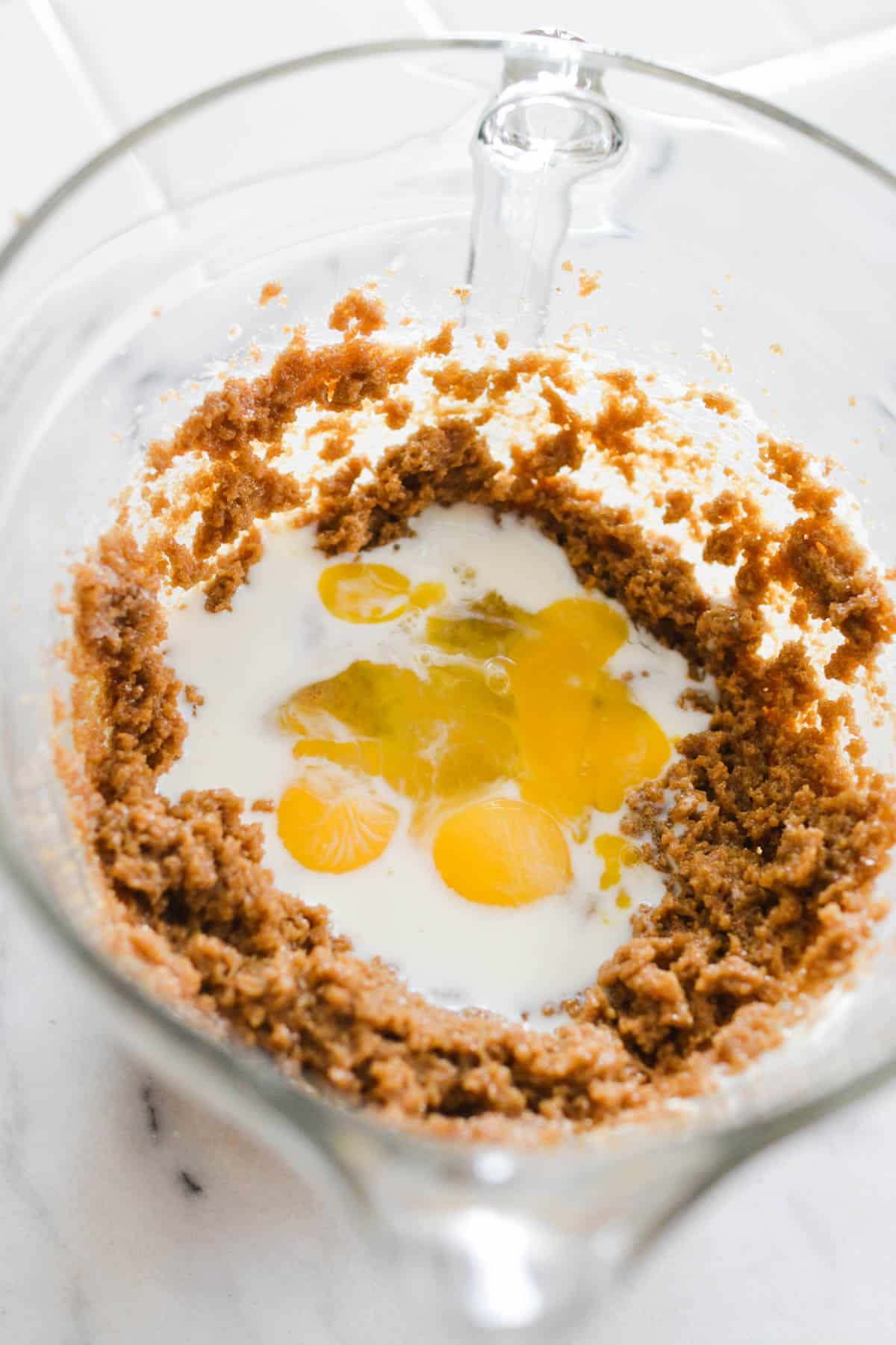 A mixing bowl with creamed brown sugar and butter with eggs and milk waiting to be mixed.