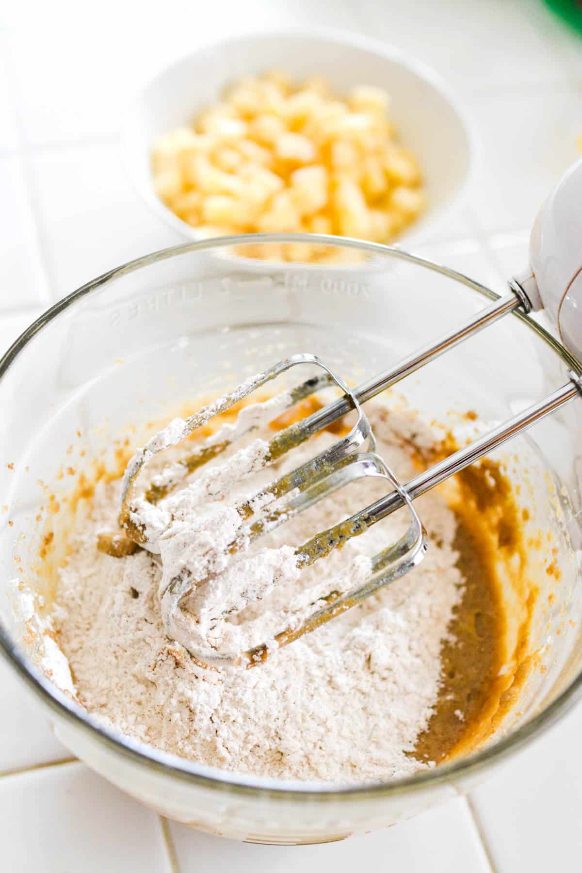 Mixing bowl with a hand mixer mixing wet and dry ingredients.