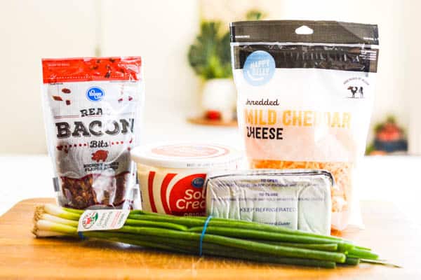 Ingredients for making a bacon cream cheese dip on a cutting board.