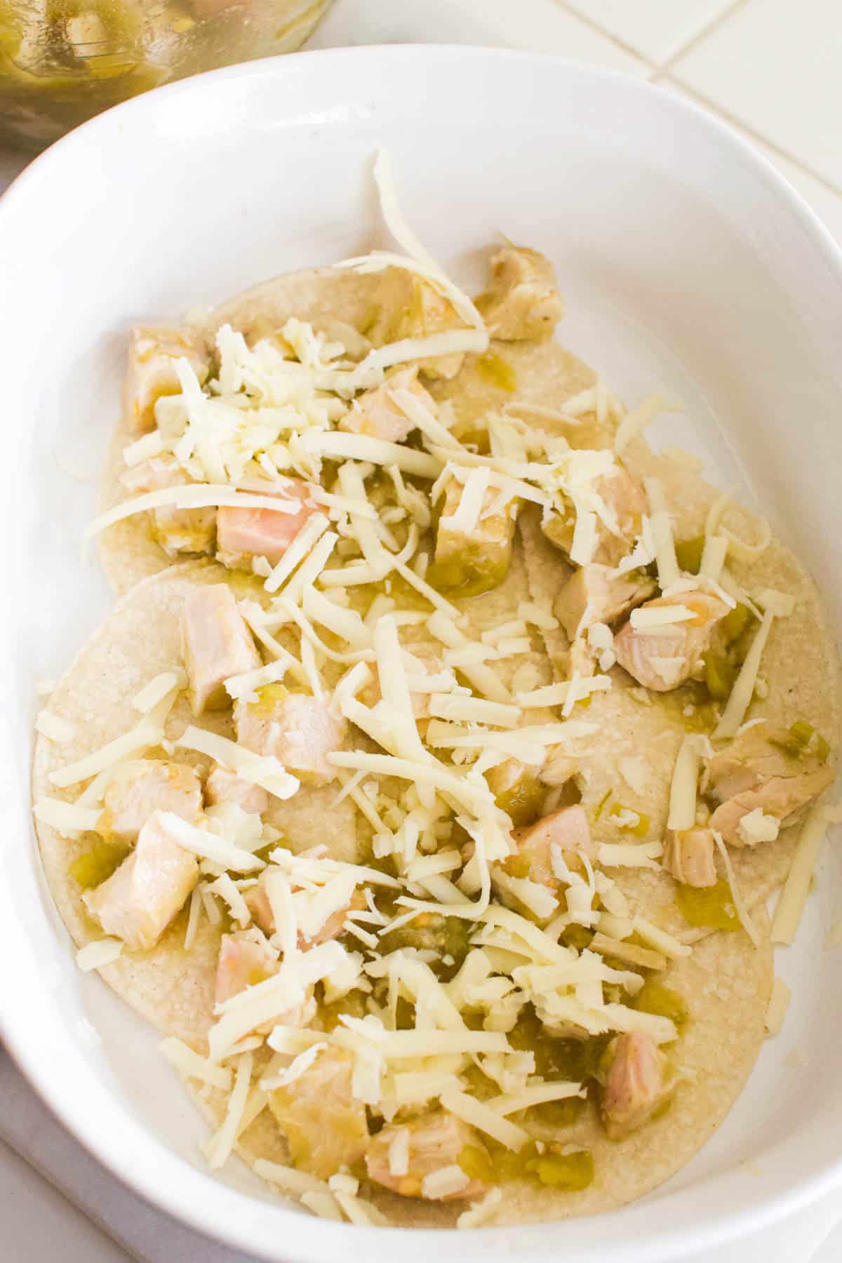 Baking dish layered with chicken, grated cheese and green chiles.