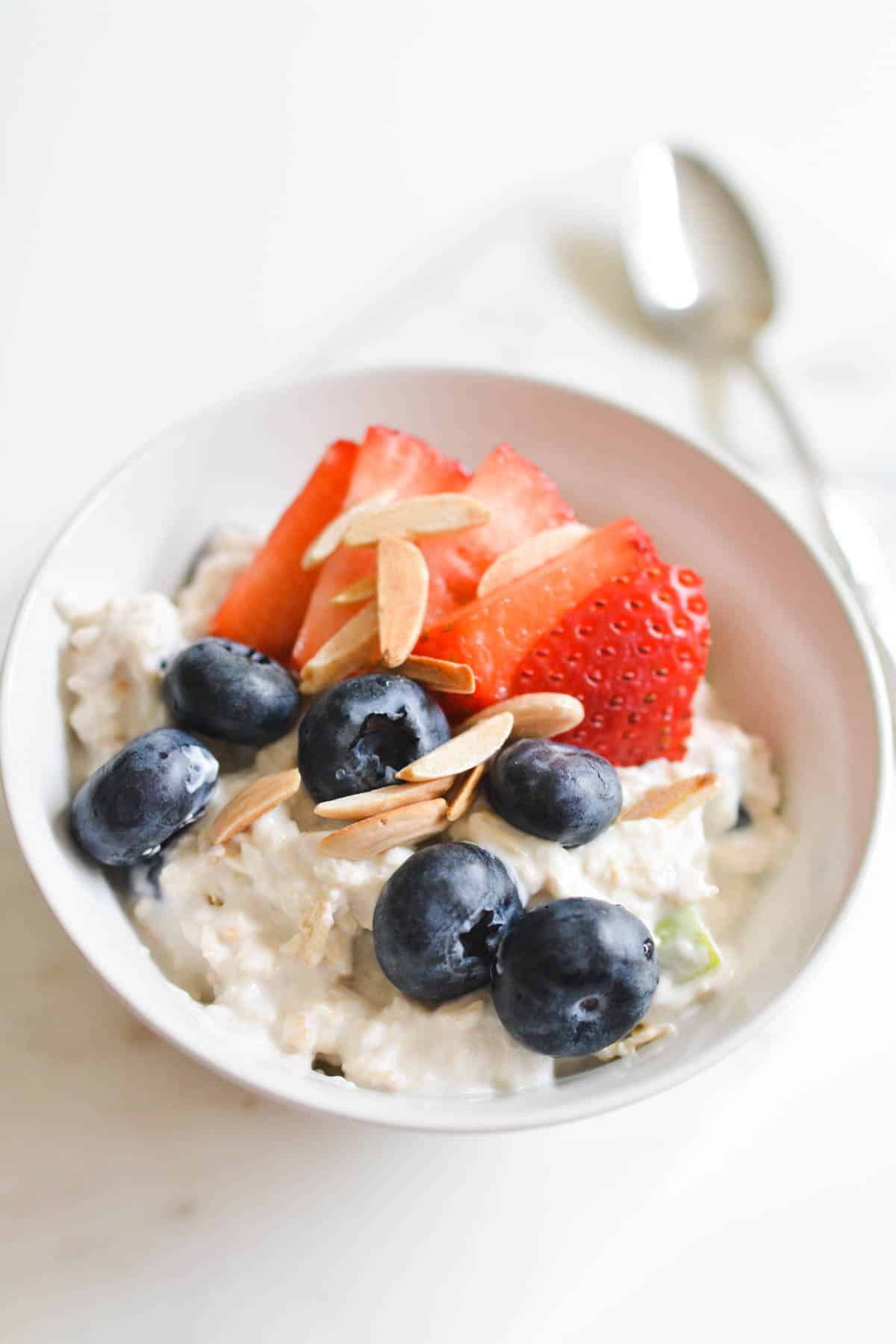 Bowl of cold oatmeal topped with fresh fruit.
