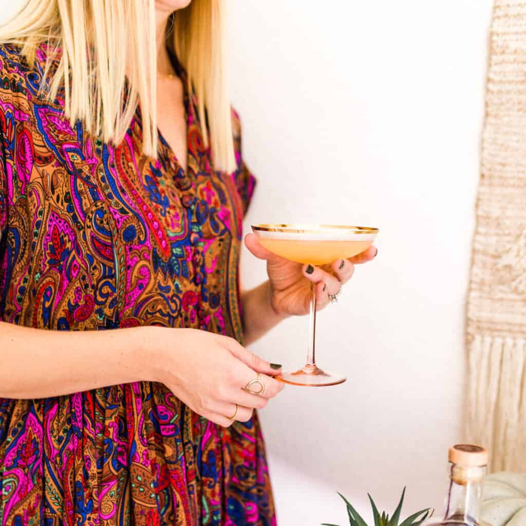 Woman holding a coupe glass with a Spiced Rum Daiquiri in it.