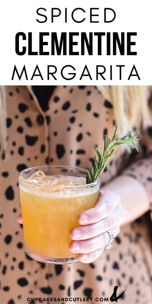 Girl holding a cocktail in her hand garnished with a sprig of fresh rosemary.