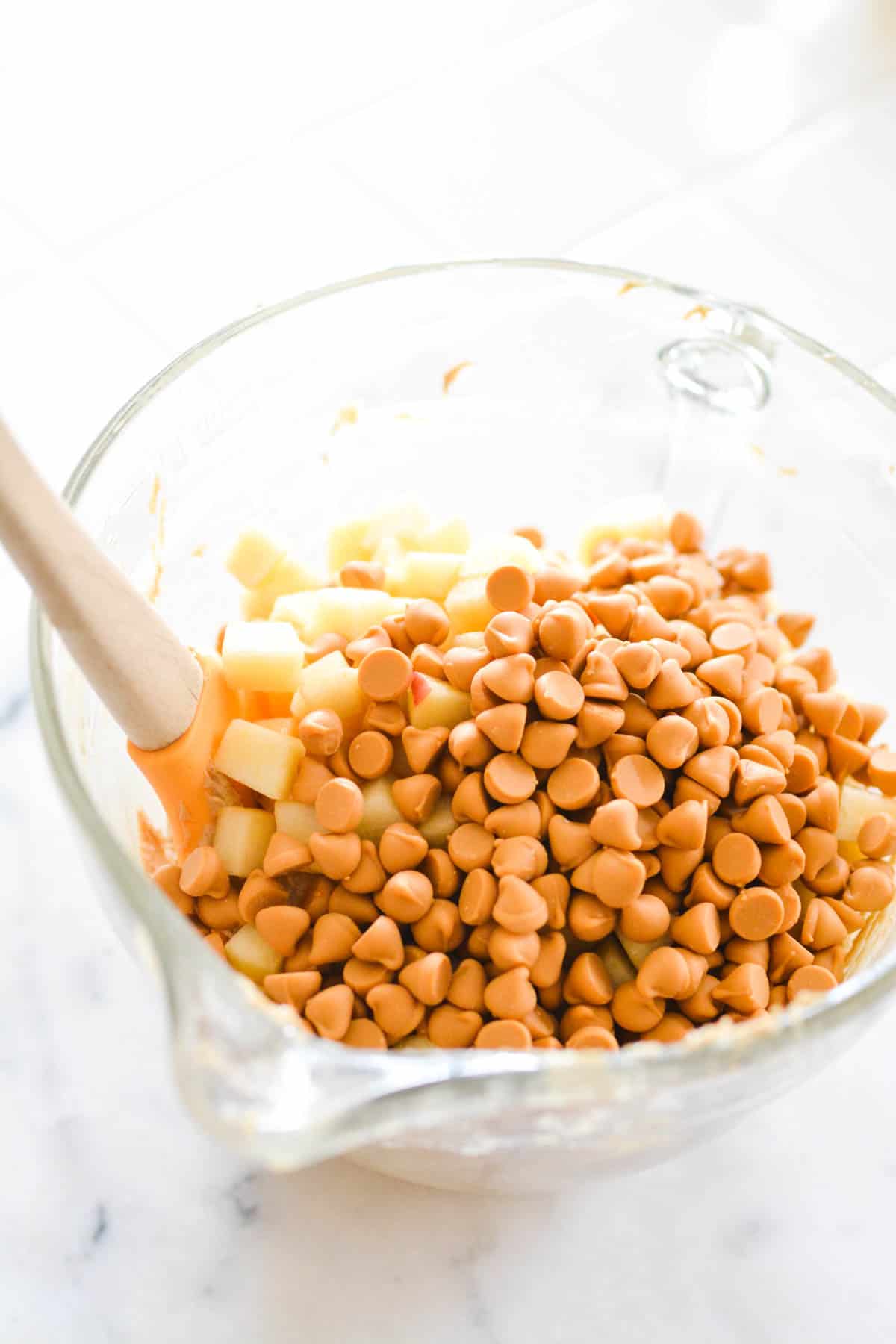 Glass mixing bowl with apples and butterscotch chips.