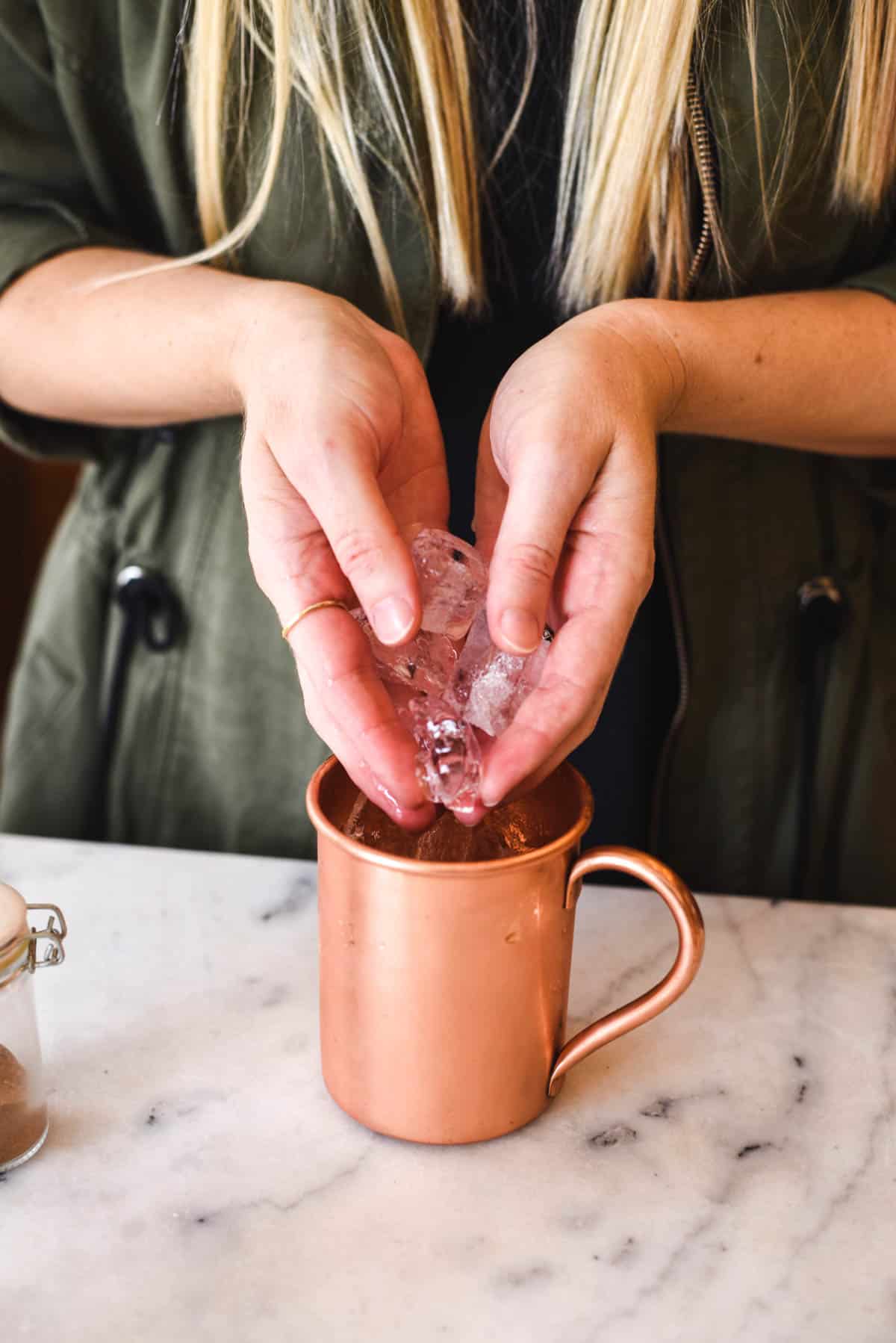 Woman adding ice to a copper Mule mug.