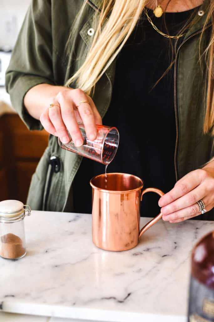 Woman adding lime juice to a copper Moscow Mule mug.