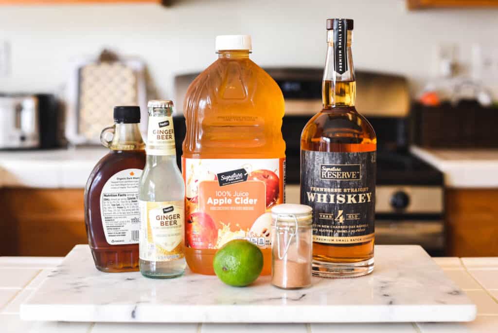 Ingredients to make an Apple Cider Moscow Mule sitting on a cutting board.