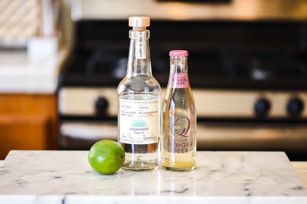 Ingredients to make a Moscow Mule with Tequila on a cutting board.
