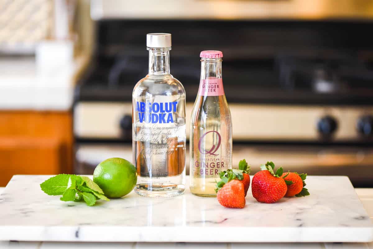 Ingredients for a Strawberry Moscow Mule with mint on a counter.