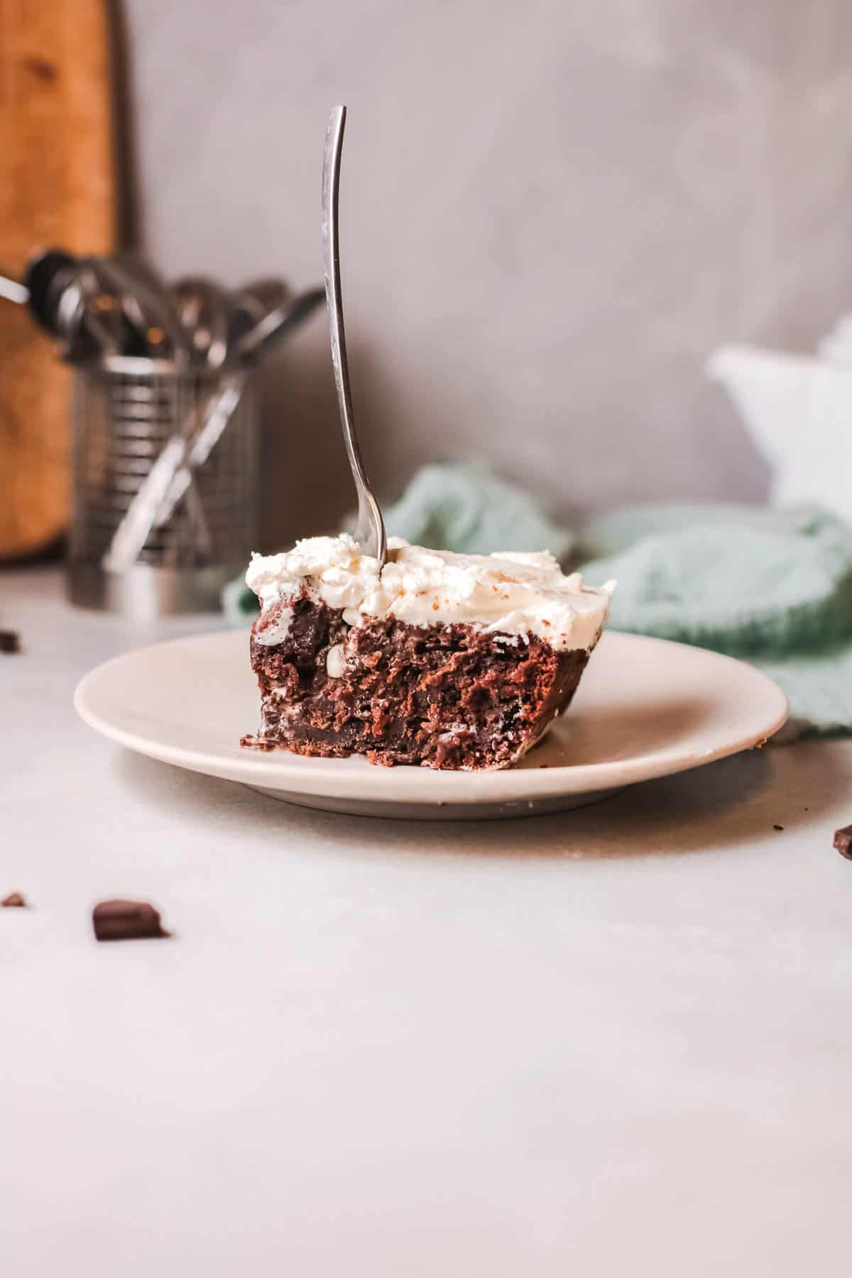 Piece of chocolate cake on a plate with a fork sticking out of it.