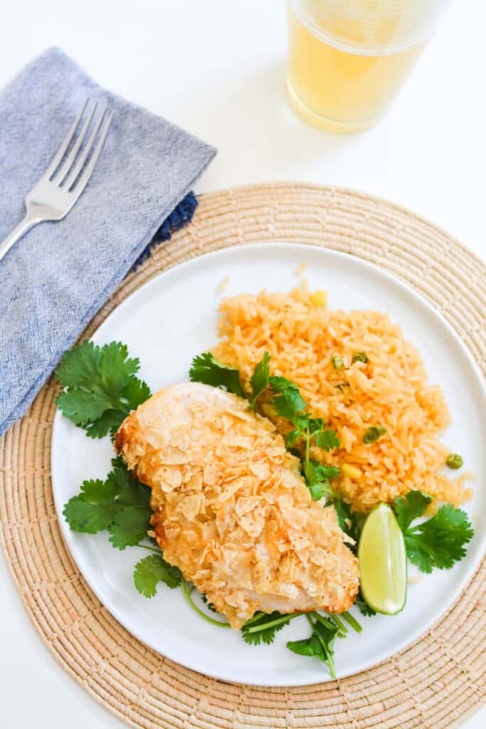 A dinner plate with baked lime chicken next to rice.