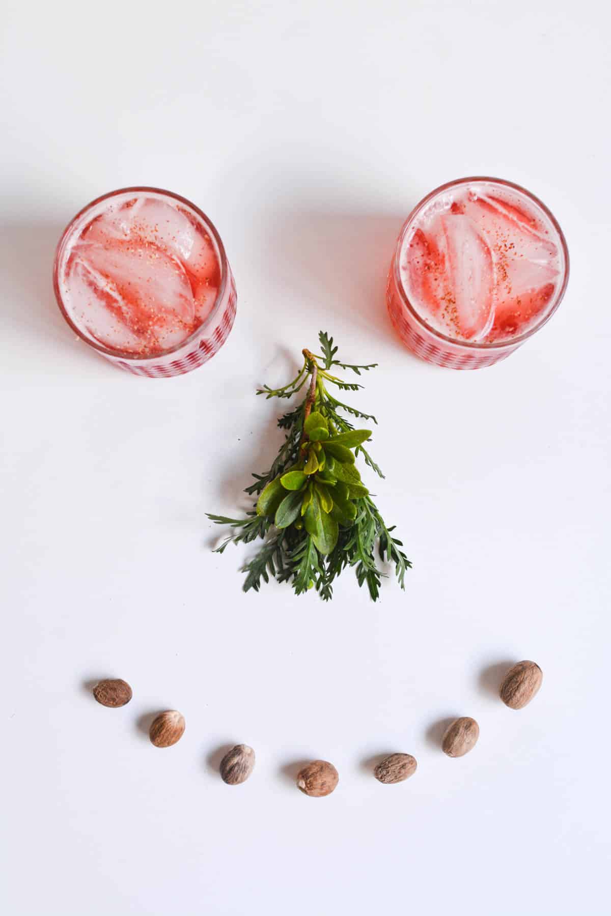 2 glasses of a cranberry cocktail as eyes for a happy face on a table.