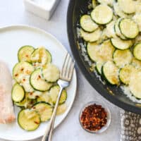 Close up of a dinner plate with sauteed zucchini topped with parmesan.