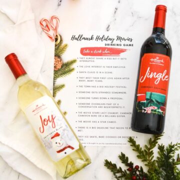 A copy of a printable Hallmark Christmas movie drinking game next to bottles of wine.