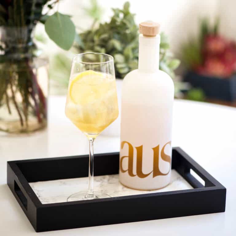 Cocktail in a wine glass on a small tray on a table.